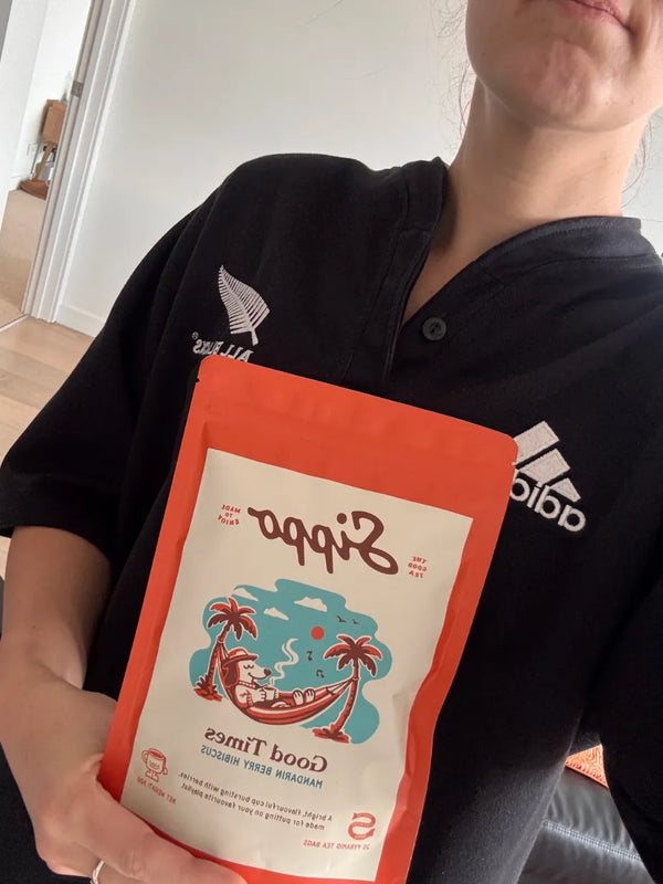 Person holding Good Times mandarin berry hibiscus tea, pack facing away from camera