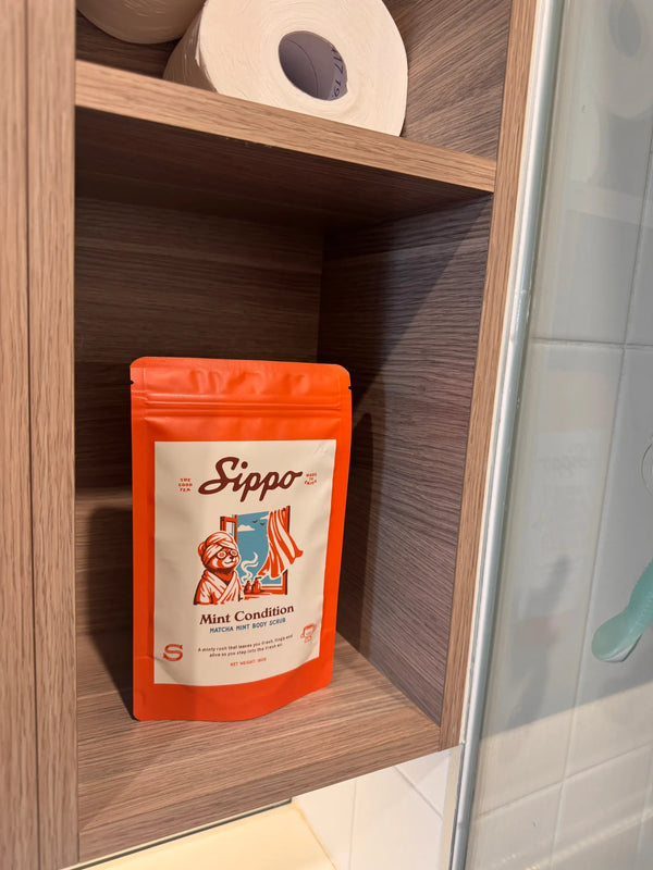 Sippo Mint Condition body scrub pouch on a wooden bathroom shelf